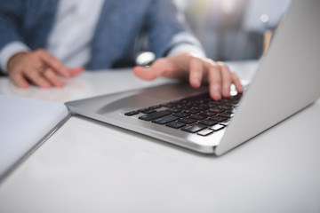Work time. Close up of male hands using laptop at work. Focus on notebook