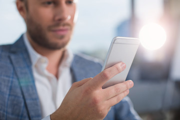 Means of communication. Close up of unshaven man holding cellphone. Focus on mobile phone