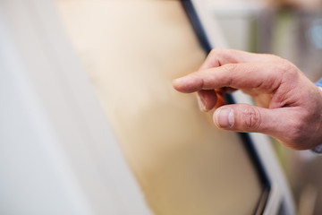 Verify orders. Close-up of fingers of man is touching display of self-service kiosk. Copy space in...