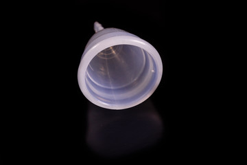 White menstrual cup isolated on a black background