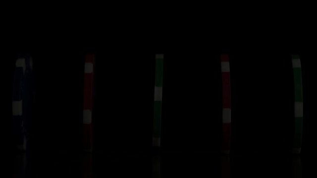 Poker chips stand in a row on a black background, a Domino effect. Playing poker chips are on the table, a symbol of casino