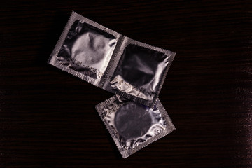 Several condoms on the dark wooden table. Top view