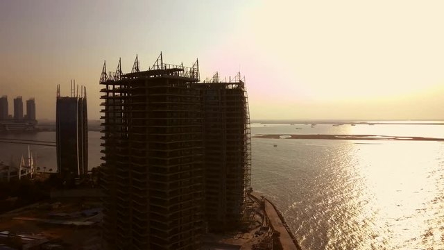 Aerial shot of apartment construction with sea view from a drone flying from left to right in Jakarta, Indonesia. Shot in 4k resolution