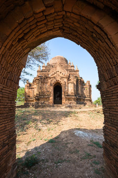 Unknown temple viewed through an arched gate in Bagan, Myanmar (Burma) on a sunny day.