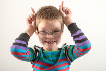 Caucasian boy in glasses shows funny faces. The guy gets vivid emotions.