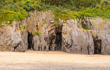 Caves formed in the amazing rocks in the cliff face at Tenby South Beach, Tenby, Wales, UK