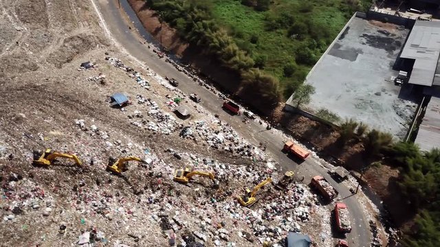 Aerial view of Bantar Gebang landfill or trash dump with backhoe and trucks. Shot in 4k resolution at Bekasi, Indonesia