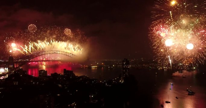 The end of New year 2018 fireworks in Sydney at night over city CBD landmarks reflecting in still waters of Harbour.
