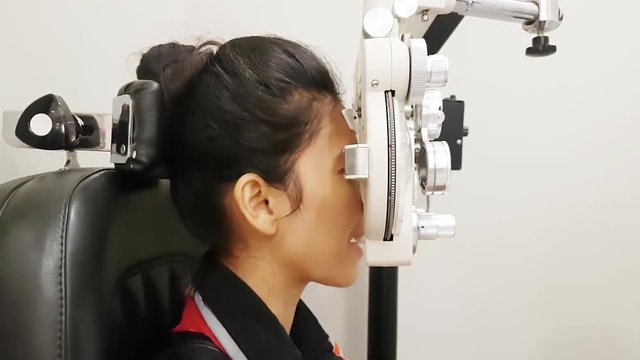 Young woman examining her eyes with phoropter in an ophthalmologic clinic
