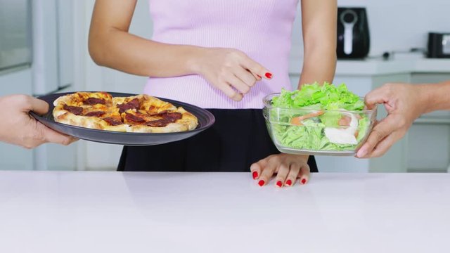 Dieting concept. Anonymous woman hands gesture removing salad and choosing to eat pizza. Shot in 4k resolution