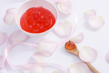 Fototapeta na wymiar Closeup of pink rose flower petals and red cream on white background for beauty cream. Beauty cream 