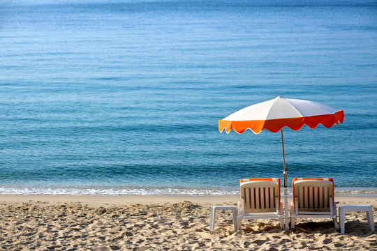 Luxury tropical caribbean beach resort sunbathing umbrella and lounger chair on sand deep blue sea summer holiday vacation photo