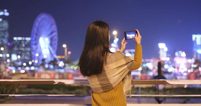 Woman taking photo on cellphone in night view