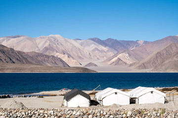 Landscape image of Pangong lake with small camps , mountains view and blue sky background