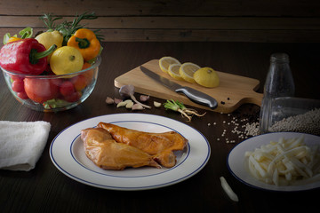 Prepare grill chicken with pepper and salt in white dish and ingredient in kitchen which has dim light