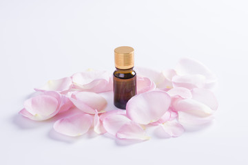 Obraz na płótnie Canvas Aromatherapy oils with rose flower petals on white background. 