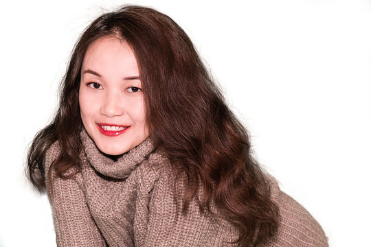 A portrait of a young oriental girl with long wavy hair, wearing turtleneck sweater