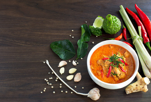 Chicken panang curry in the white bowl and fresh spice on brown wooden background Thai food