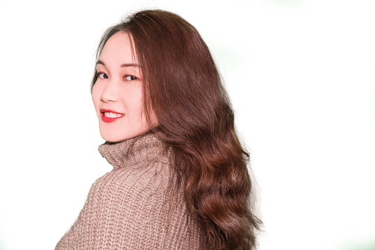 A portrait of a young oriental girl with long wavy hair, wearing turtleneck sweater