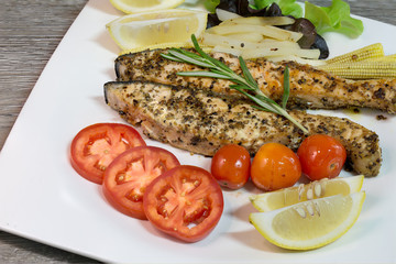 Grilled salmon with pepper and salt in white dish and ingredient in kitchen