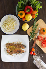 Prepare grill salmon with pepper and salt in white dish and ingredient in kitchen which has dim light