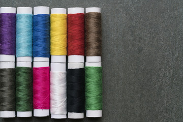 Colored thread coils on black background, top view