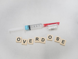 Obraz premium Tan tiles with black capital letters spelling Pain Killer with a syringe and empty glass Fentanyl vial on a tan tile background.