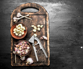 Fresh garlic with a press tool on a wooden board.