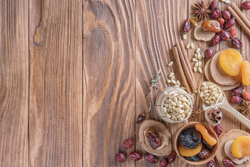 Mix of nuts, dried fruits, dried rose hips, and spices on a rustic wooden background. Concept of healthy snack. Various nuts and dried fruits.