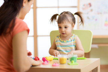 child kid girl and mother play colorful clay toy at nursery or kindergarten