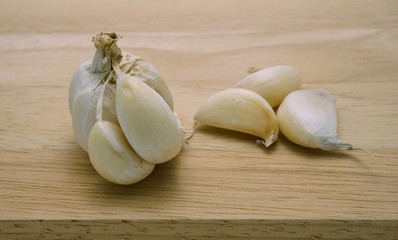 Garlic bulb and its cloves on wooden table background; after peeling outer shell. A type of cooking ingredient. Herbal plants and healthy food related to blood pressure, antibiotics, etc.