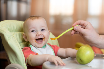 Baby eating healthy food with father help at home