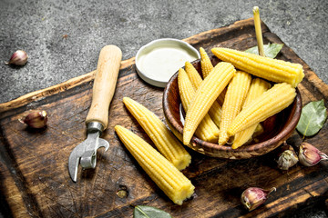Pickled corn in a jar on a cutting board.