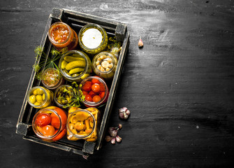 Preserves vegetables in glass jars in an old box.