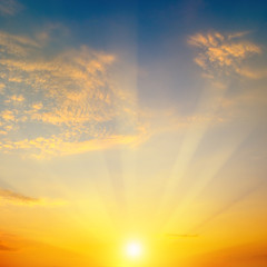 Cloudy sky and bright sun rise over the horizon.