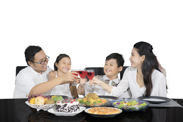 Cheerful family is toasting glasses before having meals