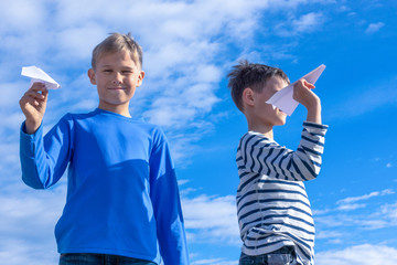Children throwing white paper plane.