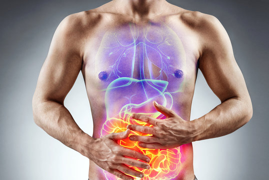 Man holding his stomach in pain. Photo of man with naked torso experience irritable bowel syndrome on grey background. Medical concept