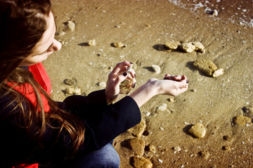 Girl sprinkles perfume on her wrist against the sea
