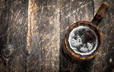 Fresh beer in a wooden mug.