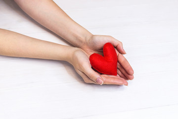 woman hands holding heart figure made from red fabric