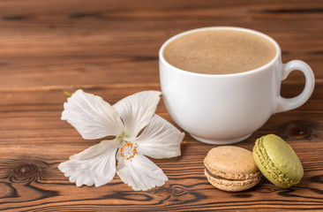macarons cake, cup of coffee and hibiscus flower on wooden background