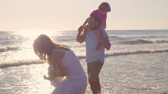 Young family walking on beach in sunset