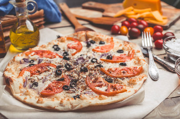 Pizza Margarita on thin crust. Food composition on a wooden background. Mediterranean traditional cuisine. Easy vintage toning