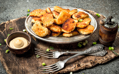 Chicken nuggets with cheese sauce on the board.