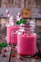 pink smoothie with wild cranberries in mason jar with mint and straw on wooden background