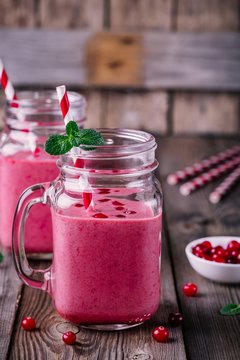 pink smoothie with wild cranberries in mason jar with mint and straw on wooden background
