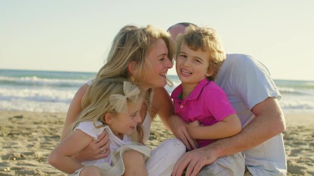 Young family sitting together on beach