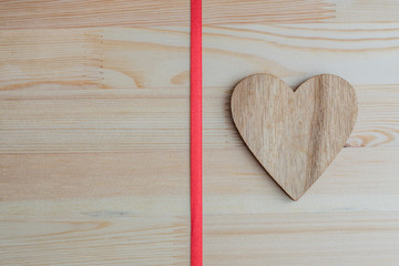 wooden heart on wooden background with red ribbon