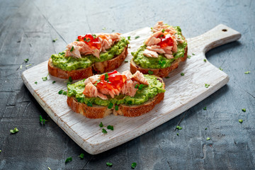 Homemade Toast sandwich with Salmon, Avocado and chilli jam on wihte wooden board. healthy food
